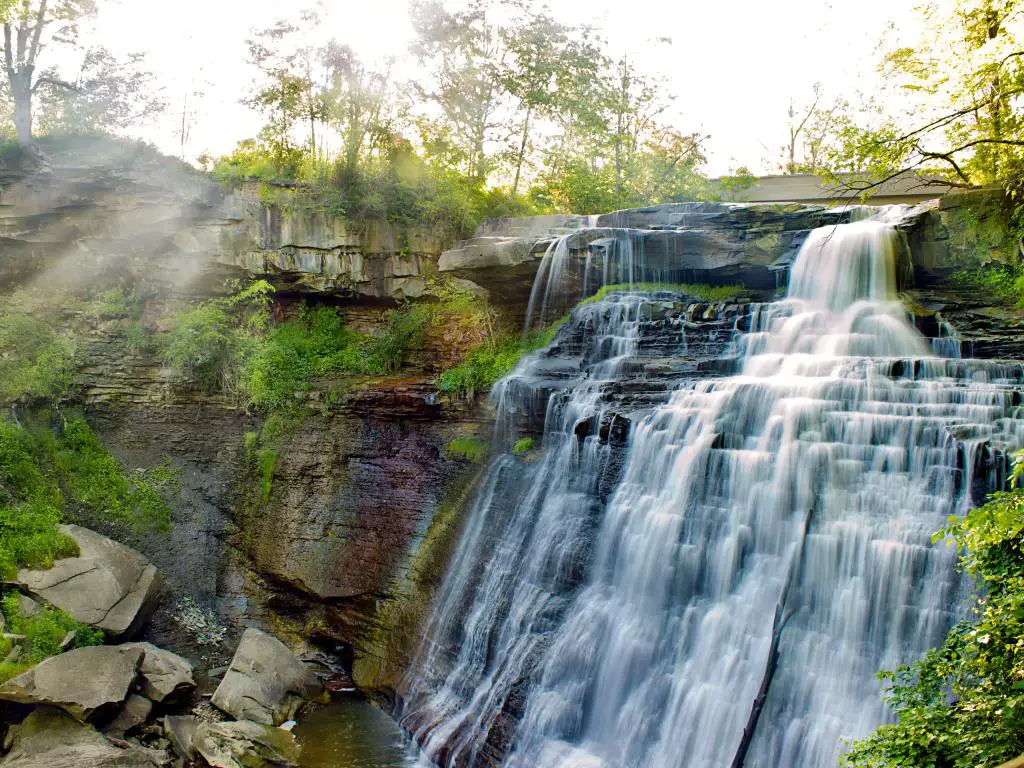 El agua que fluye con árboles a los lados en Brandywine Falls en el Parque Nacional Cuyahoga Valley en un día brillante.