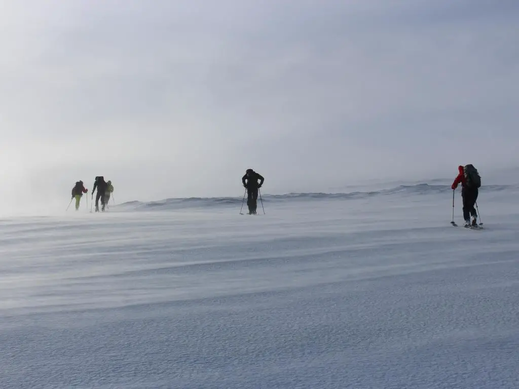 Un grupo de esquiadores de montaña subiendo con un viento muy fuerte.  Invierno en Escocia en las montañas de Cairngorm.