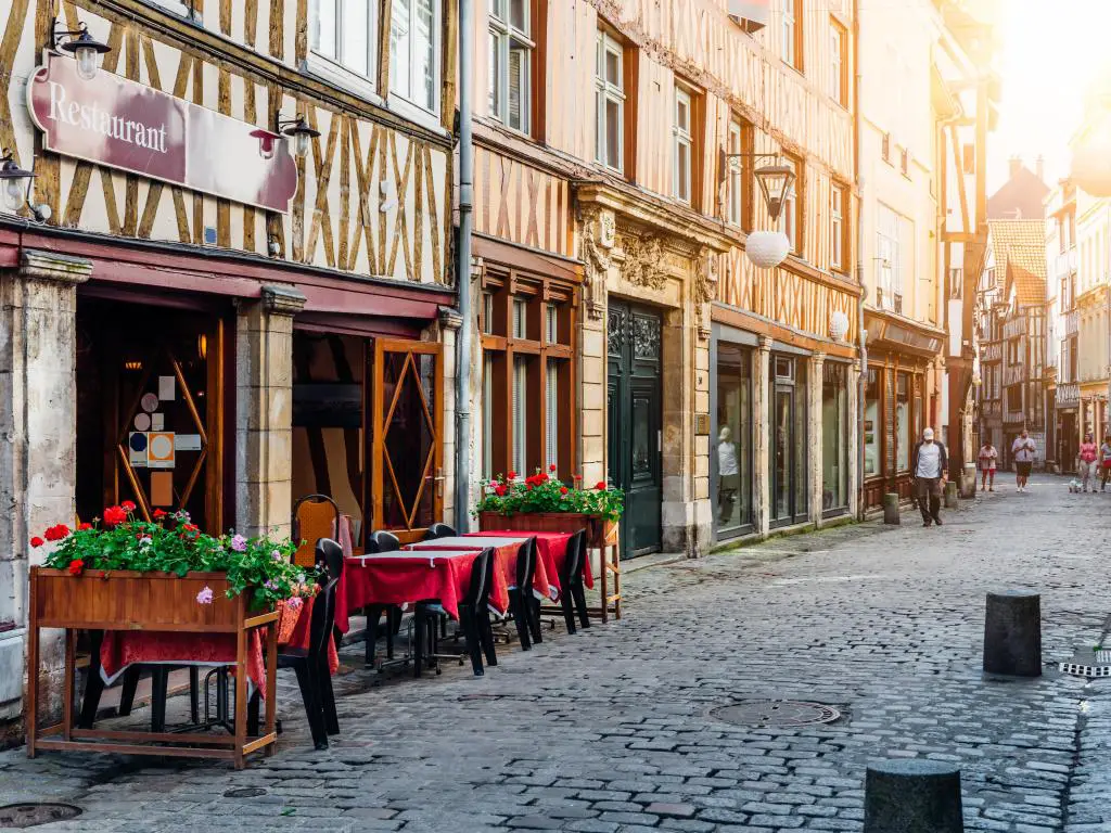 Acogedora calle con casas de entramado de madera y mesas de restaurante en Rouen, Normandía, Francia