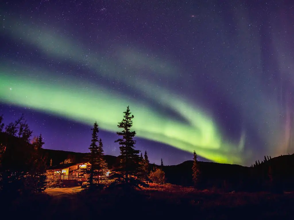 La aurora boreal brilla sobre el Parque Nacional Denali en Alaska.  Luz verde que brilla sobre las cabañas 