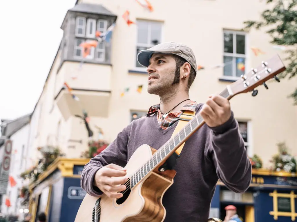 Hombre ejecutante de la calle tocando la guitarra en la calle Galway.  Irlanda