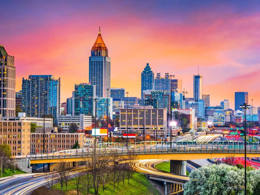 El ajetreado centro de Atlanta al atardecer, con un cielo de color púrpura y naranja y las luces traseras del tráfico