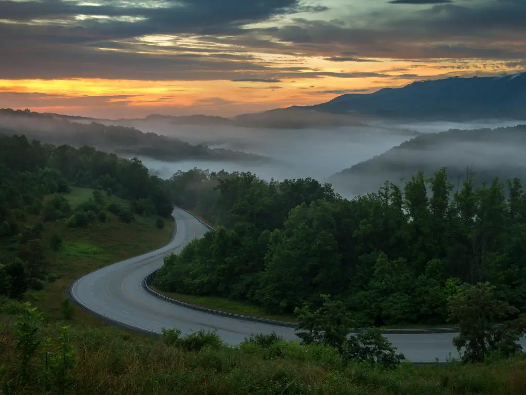 Montañas Apalaches, Carolina del Norte, EE.UU. tomadas en una mañana sobre un sinuoso camino rural con las montañas en la niebla a lo lejos.