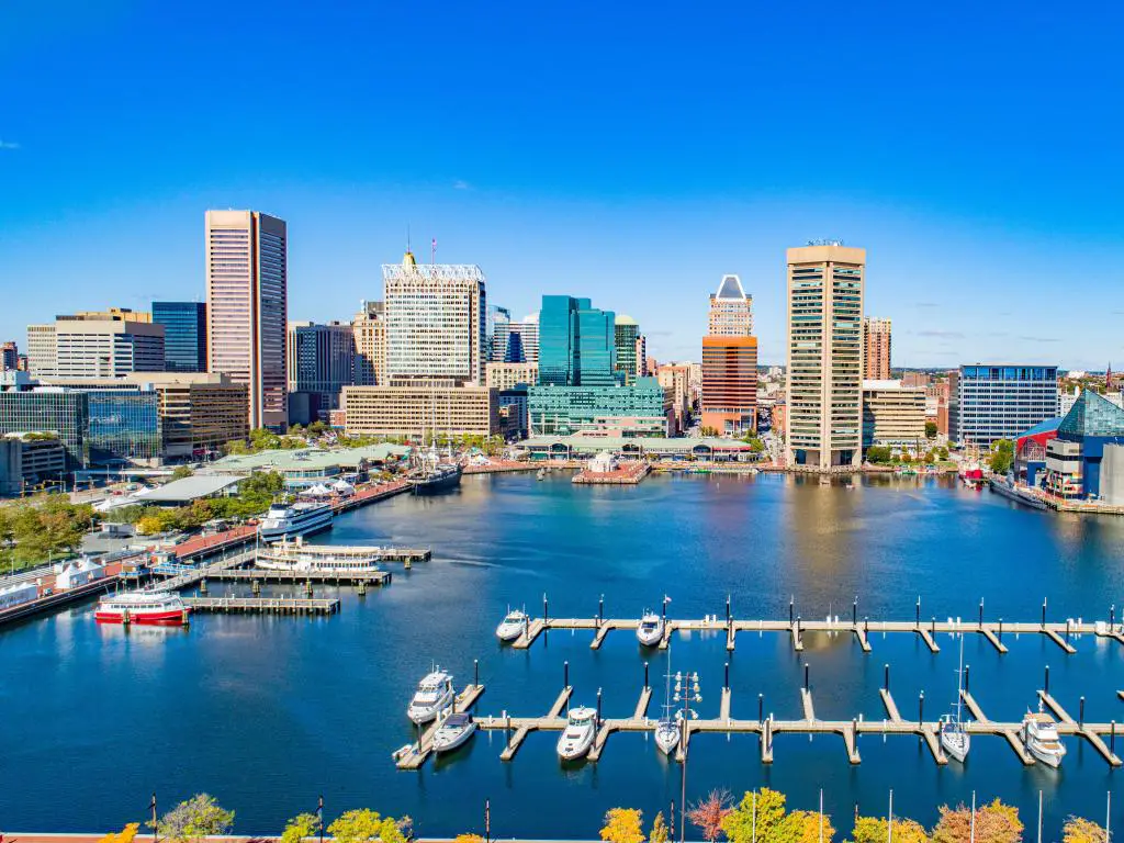 Baltimore, Maryland, EE.UU. tomada en el Inner Harbor como una vista aérea con barcos en primer plano y el horizonte de la ciudad en el fondo en un día soleado.