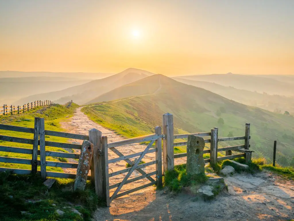 The Great Ridge en Peak District, Inglaterra, tomada al amanecer con una valla y un camino que conduce a las colinas en la distancia.  