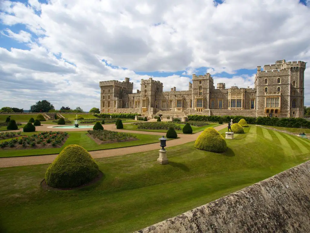 Castillo de Windsor, Londres, Reino Unido con un jardín formal en primer plano y el castillo en la distancia.