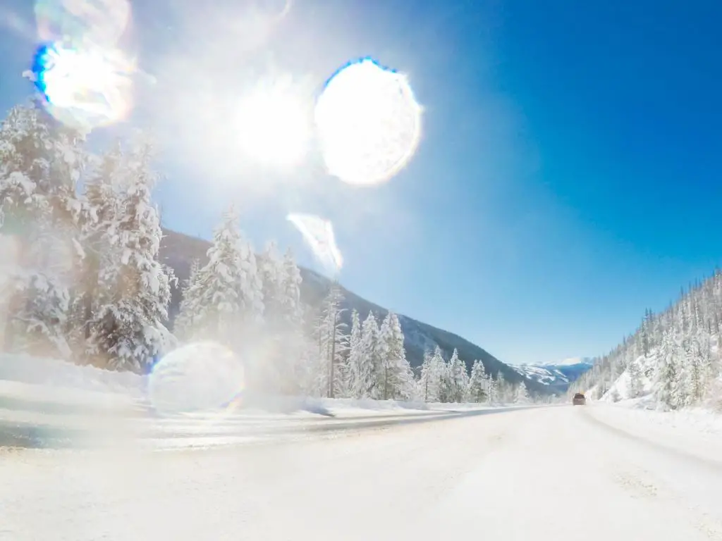 Toma tomada desde el punto de vista de un conductor, conduciendo a través de una carretera nevada de las Montañas Rocosas después de una tormenta de nieve