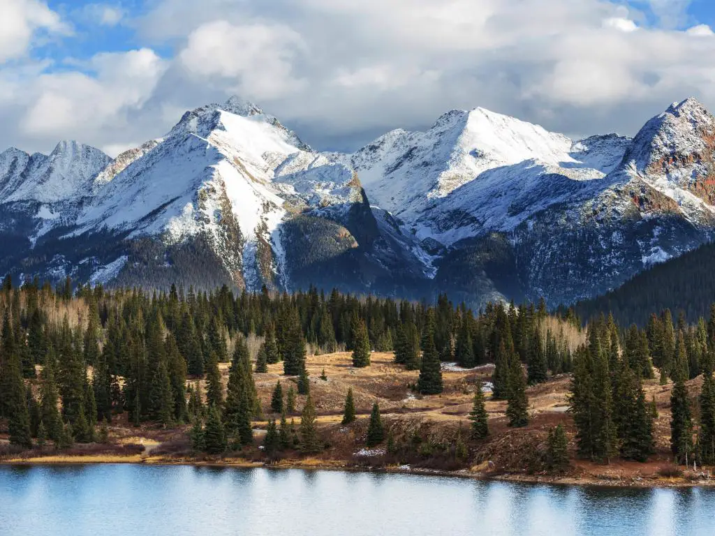 Colorado Rocky Mountains, Colorado, EE. UU. Con un paisaje montañoso cubierto de nieve, un lago y árboles en primer plano.