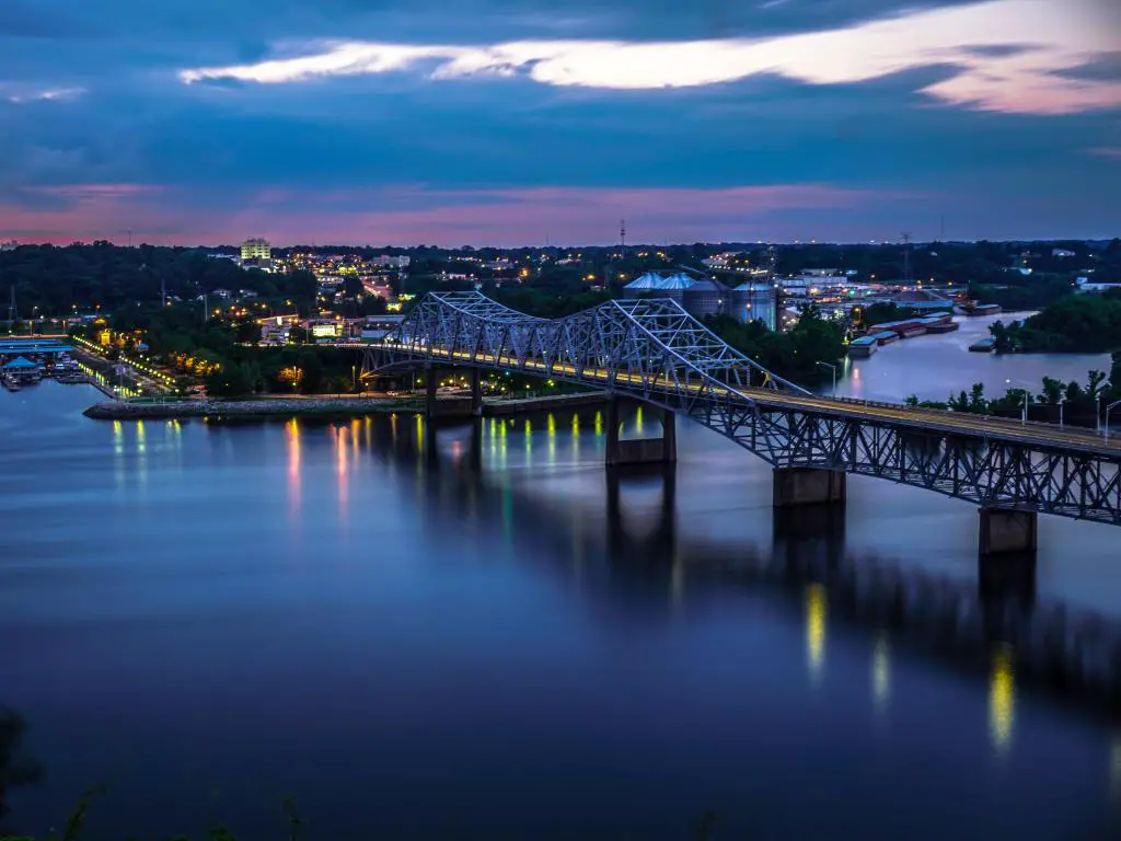 El puente O'Neil de hierro forjado en la noche, cruzando el río Tennessee cerca de Florence, Alabama.  Luces que se reflejan en el agua
