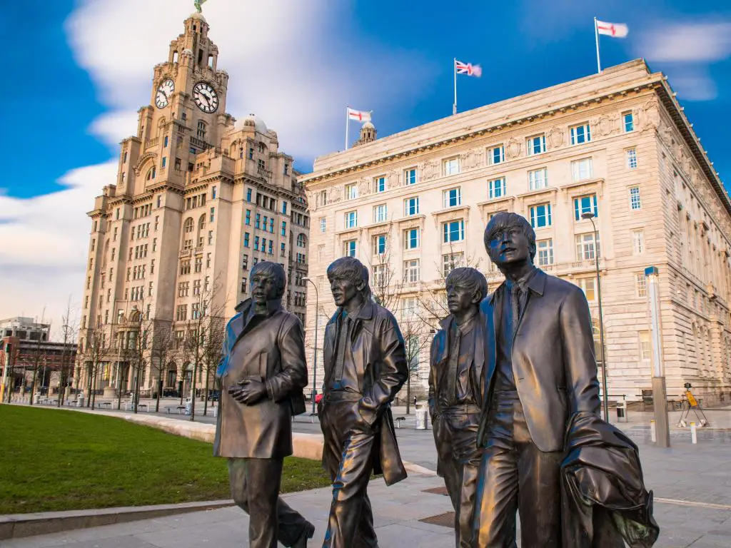 Liverpool, Reino Unido, con la estatua de bronce de los cuatro puestos de los Beatles de Liverpool en Liverpool Waterfront, esculpida por la escultura Andrew Edwards, en primer plano.