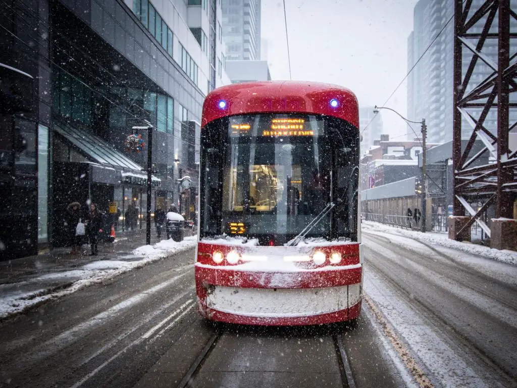 Tranvía rojo brillante en la nieve que se dirige a lo largo de las carreteras principales en Toronto, Canadá
