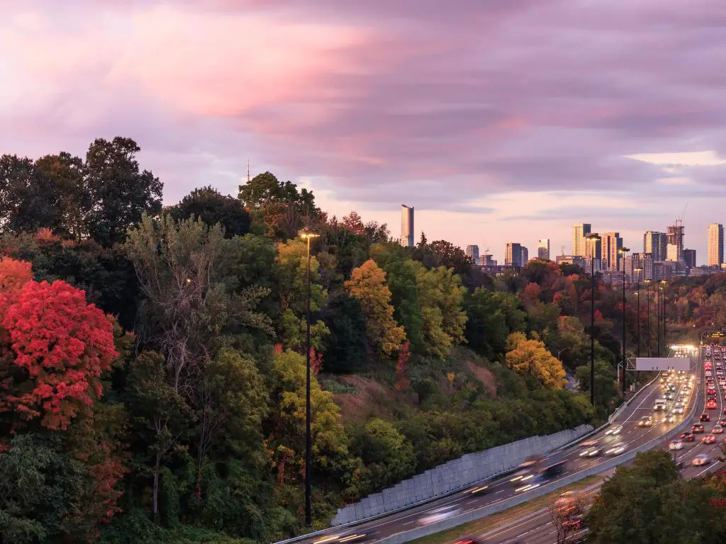 Coches que se acercan al centro de Toronto a través de Don Valley Parkway en el pico de color del otoño al amanecer, Ontario, Canadá
