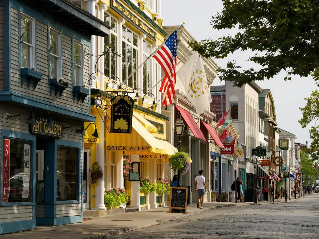 Coloridos edificios de madera que albergan tiendas bordean las calles del histórico Newport, Rhode Island.  Banderas en primer plano