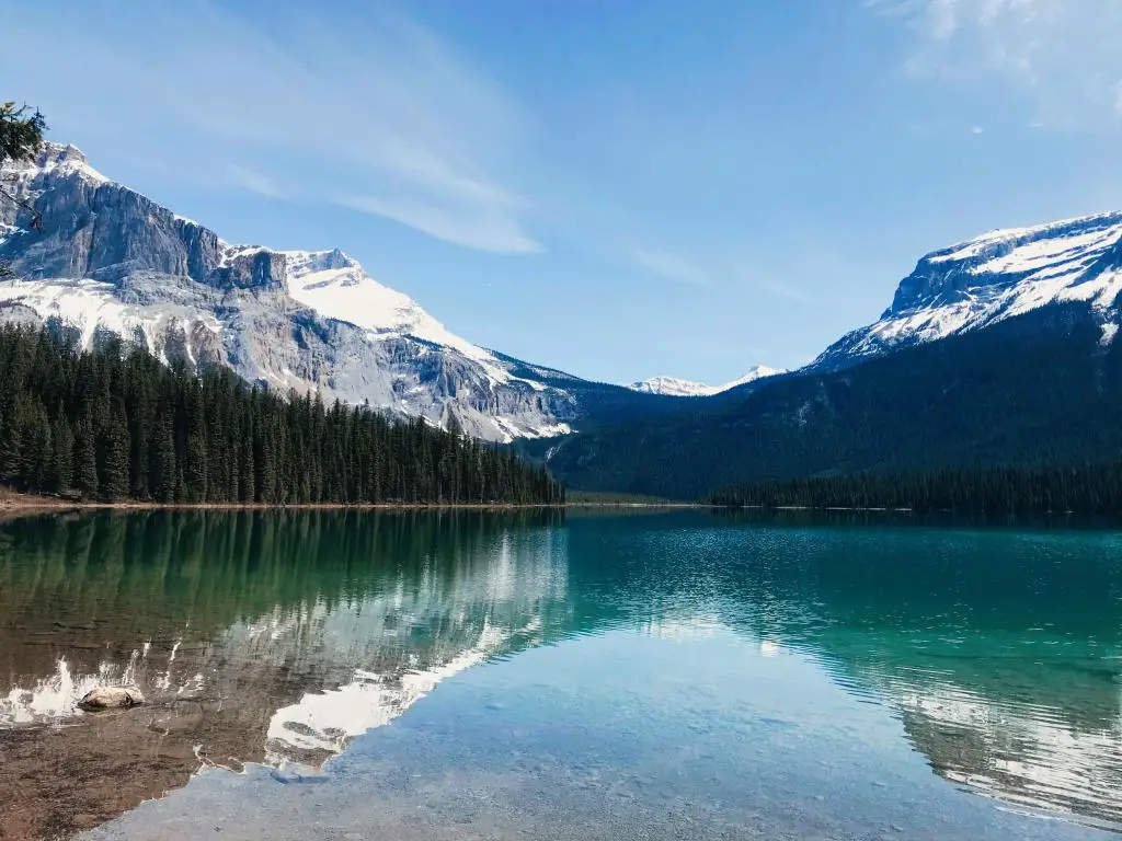 Canadian Rocky Mountains, Canadá con un lago en la distancia que refleja los árboles y las montañas cubiertas de nieve en la distancia tomada en un día soleado.