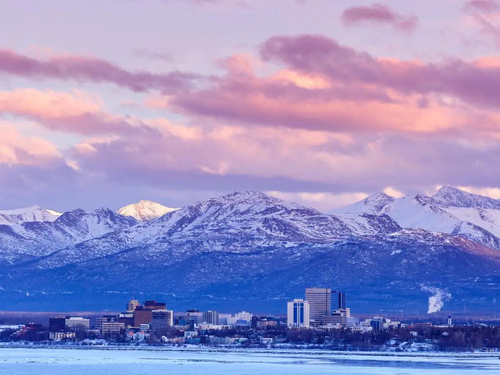Anchorage, Alaska, EE.UU. con el horizonte de la ciudad en invierno al atardecer con las montañas Chugach detrás.
