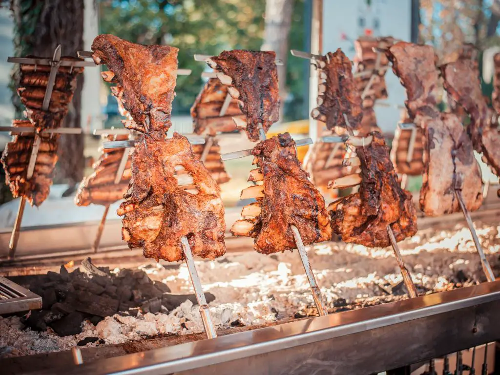 Asado tradicional argentino estilo barbacoa que cocina grandes porciones de carne de res y cordero en parrillas verticales