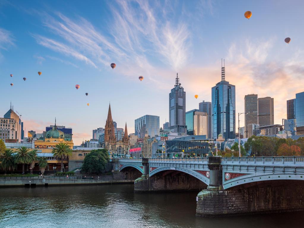 Melbourne, Australia, con el horizonte de la ciudad al atardecer y globos en el cielo.