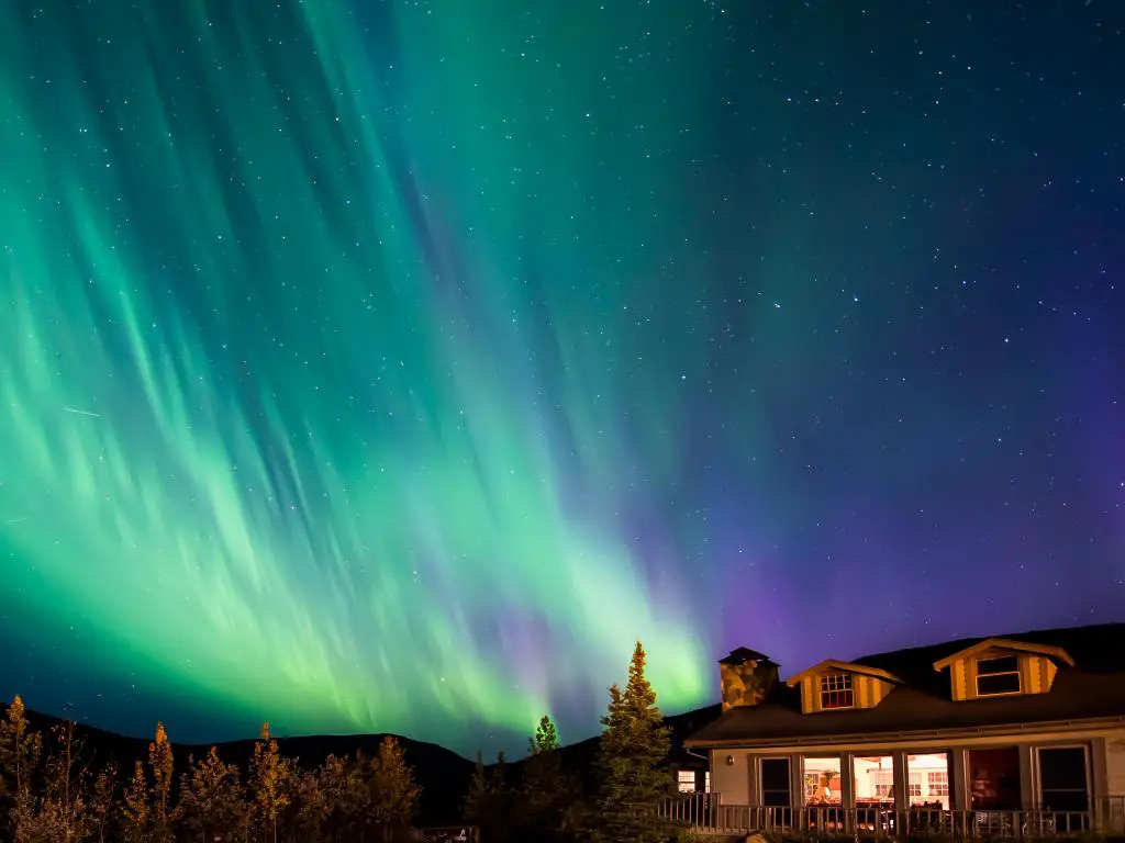 Lodge ubicado cerca del monte Denali, luces verdes del norte que se dispersan en el cielo nocturno 