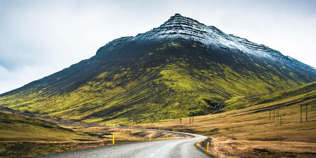 Un camino conduce a una montaña nevada a lo largo de la Ruta 1 en Islandia
