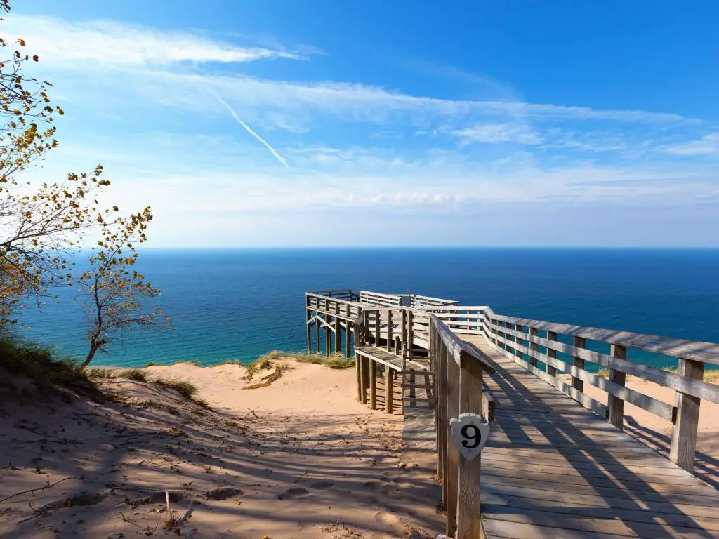 Una pasarela de madera a una playa blanca y brillante seguida de las aguas más claras y el cielo azul
