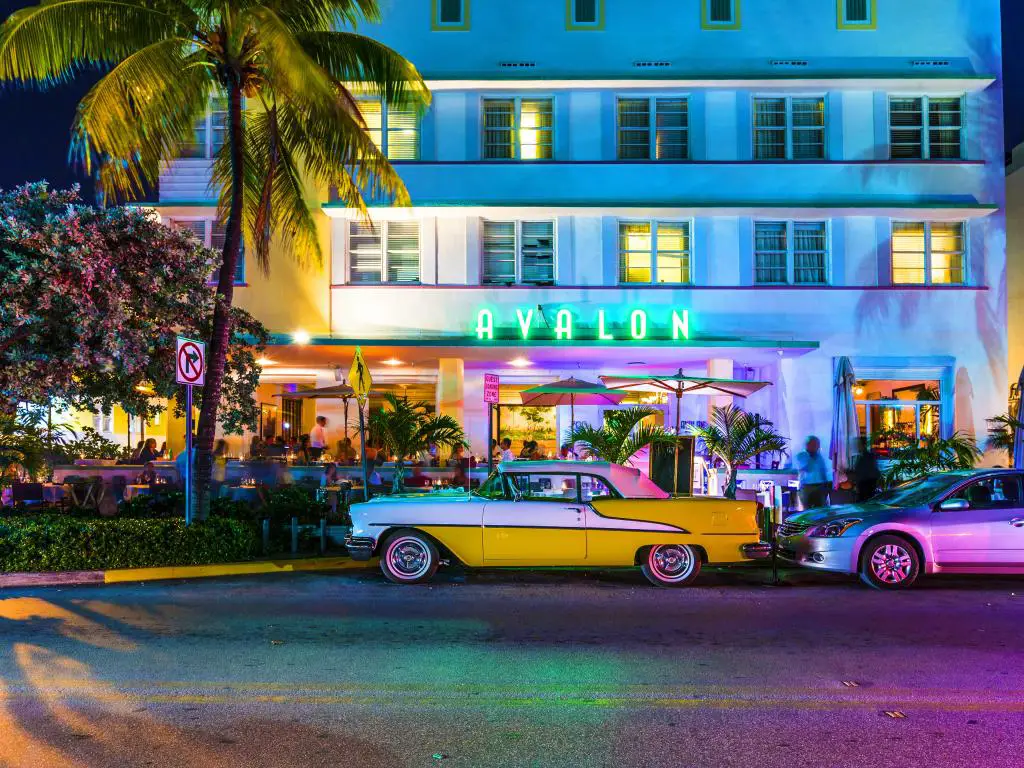 Avalon Hotel en Ocean Beach en Miami Beach por la noche con un auto antiguo estacionado afuera