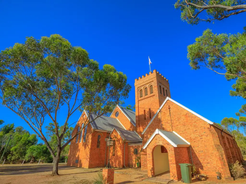 La Iglesia Anglicana de la Santísima Trinidad en Australia Occidental rodeada de cielos azules y árboles