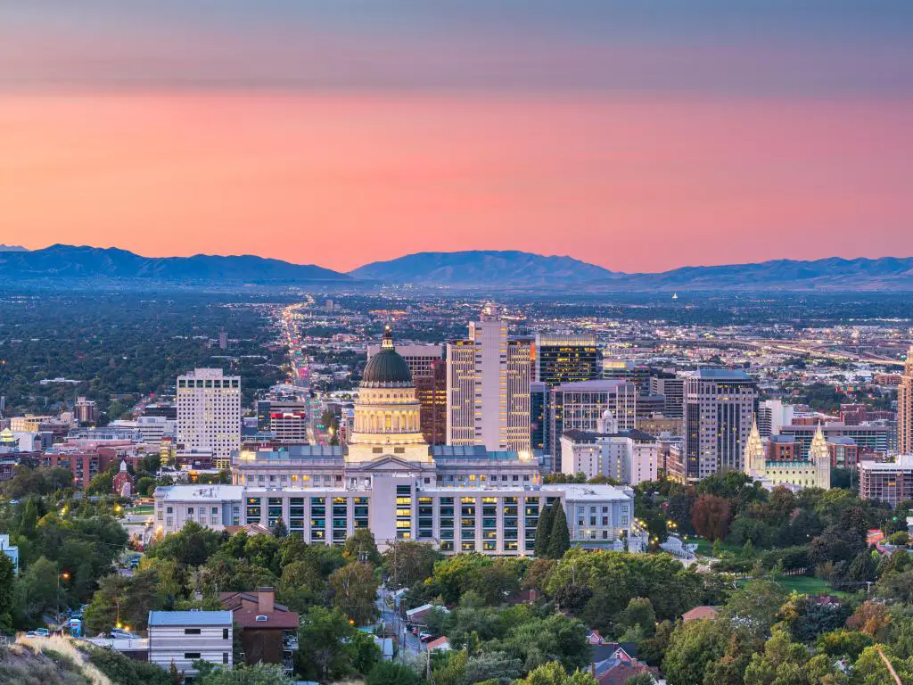 Salt Lake City, Utah, EE.UU., con vistas al horizonte del centro de la ciudad al atardecer y montañas en la distancia contra un cielo rosa.