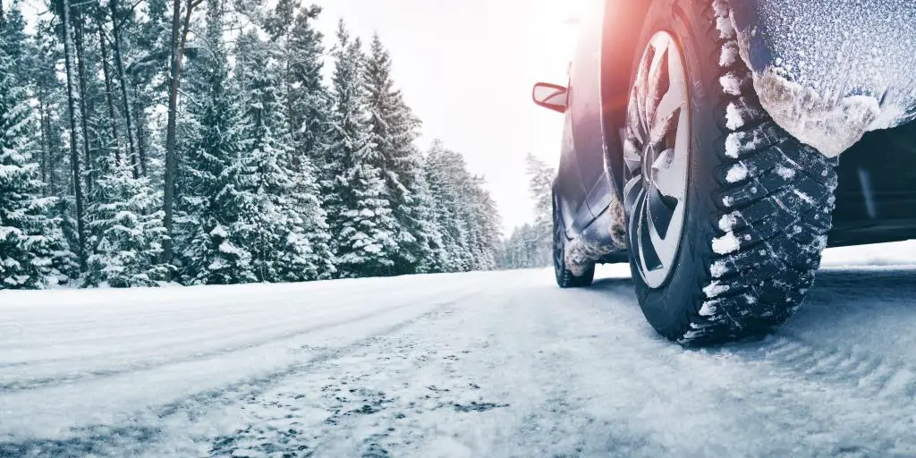 Un primer plano de los neumáticos de un coche en una carretera nevada