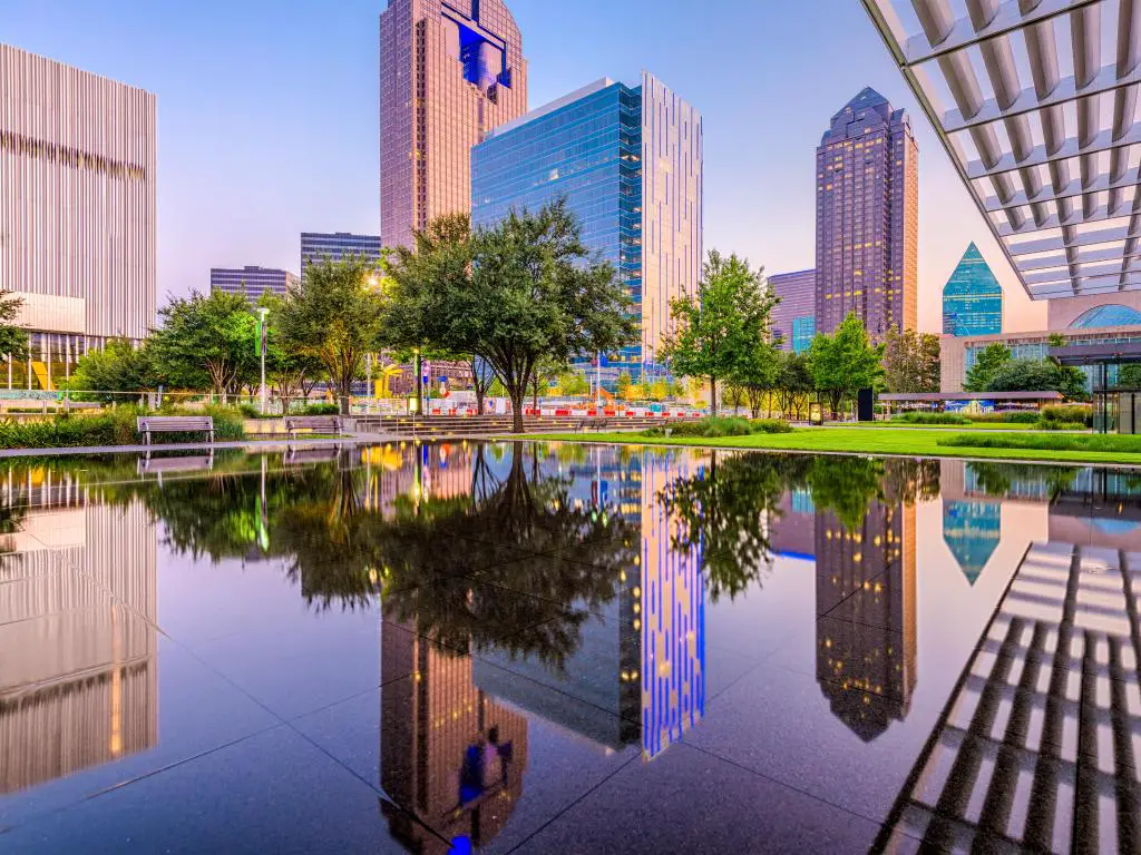 El paisaje urbano del centro de Dallas, Texas, EE.UU. al atardecer con agua en primer plano reflejando los rascacielos. 