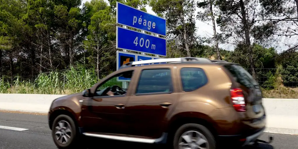 Un automóvil de bronce en una carretera francesa con un cartel azul de 'Péage 400m' en el fondo