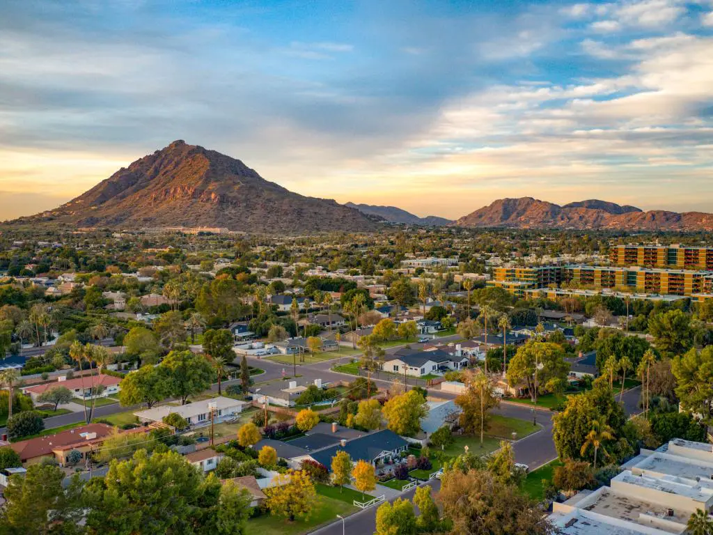 Scottsdale, Arizona, EE. UU., con un atardecer urbano sobre el centro de Scottsdale, Arizona, y las montañas a lo lejos.