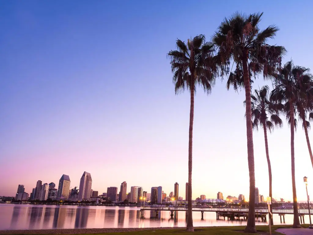 Coronado Island, California, EE.UU. con vistas a las palmeras de California y la ciudad de San Diego en la distancia tomada al atardecer.