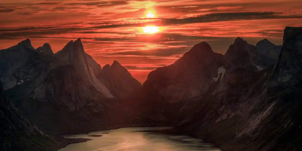 Cielos anaranjados causados ​​por el sol de medianoche sobre la montaña Reinebringen, Noruega, en verano