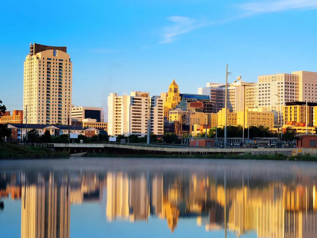 Rochester, Minnesota, EE.UU. con el horizonte de la ciudad en la distancia y el río en primer plano tomado en un día soleado.