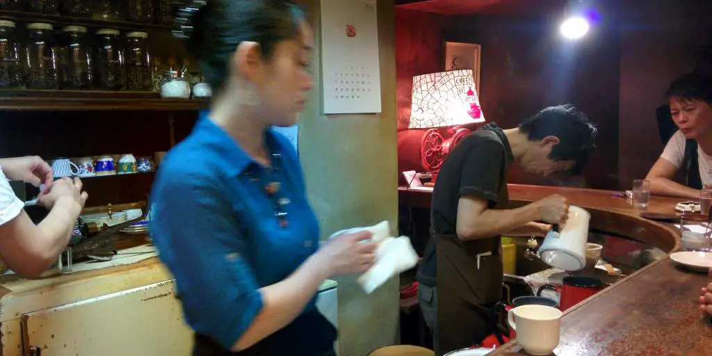 Baristas sirviendo café a los clientes en el bar del Café de l'Ambre de Tokio