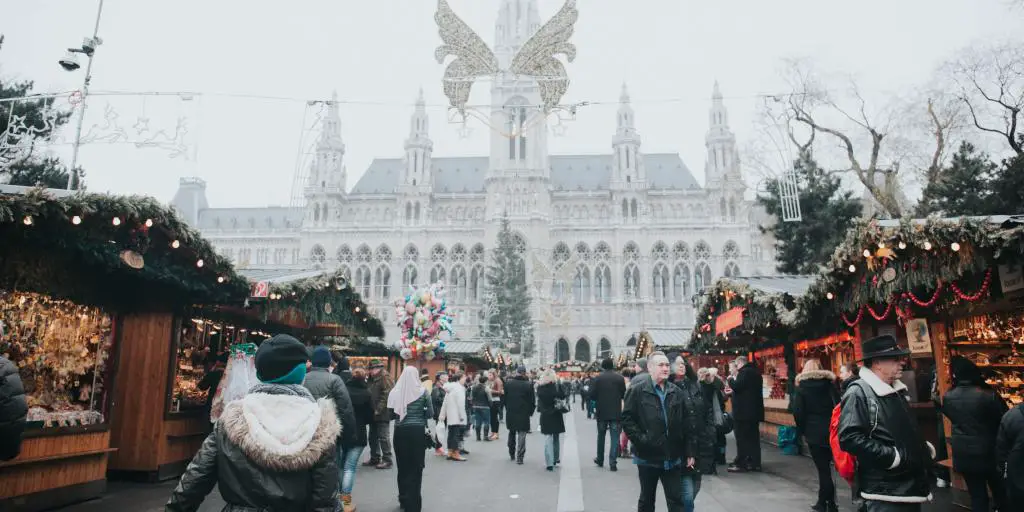 La gente camina por un mercado navideño frente al Ayuntamiento de Viena