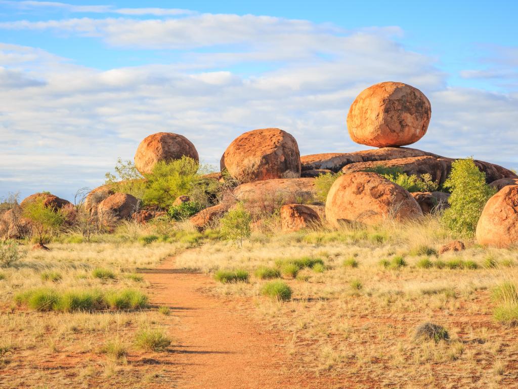 Devil's Marbles/Karlu Karlu, Australia con una roca principal y otras sobre una formación rocosa natural en un día soleado.