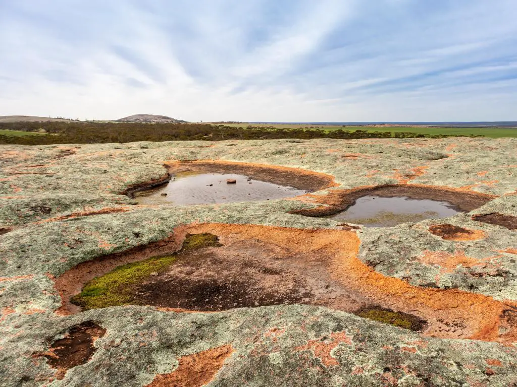 Parque Nacional Gawler Ranges, Península de Eyre, Australia del Sur con pozos de agua llenos de agua de lluvia sobre una roca de granito tomada en un día claro y soleado.