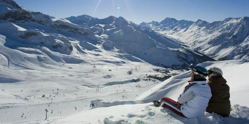Una pareja sentada en una cornisa con vistas a las pistas de esquí en Ischgl debajo