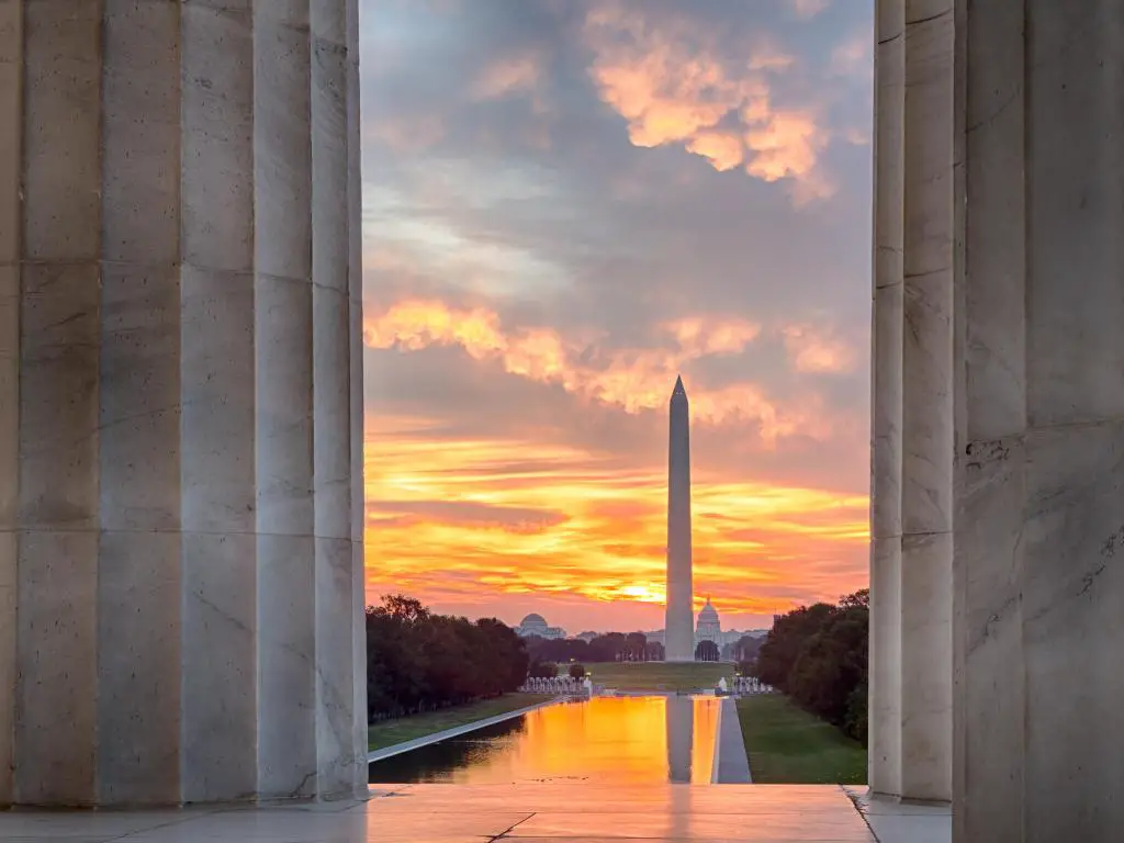 Monumento a Washington, Washington DC, EE.UU. con un amanecer rojo y naranja brillante al amanecer que refleja el Monumento a Washington en la nueva piscina reflectante junto al Monumento a Lincoln.