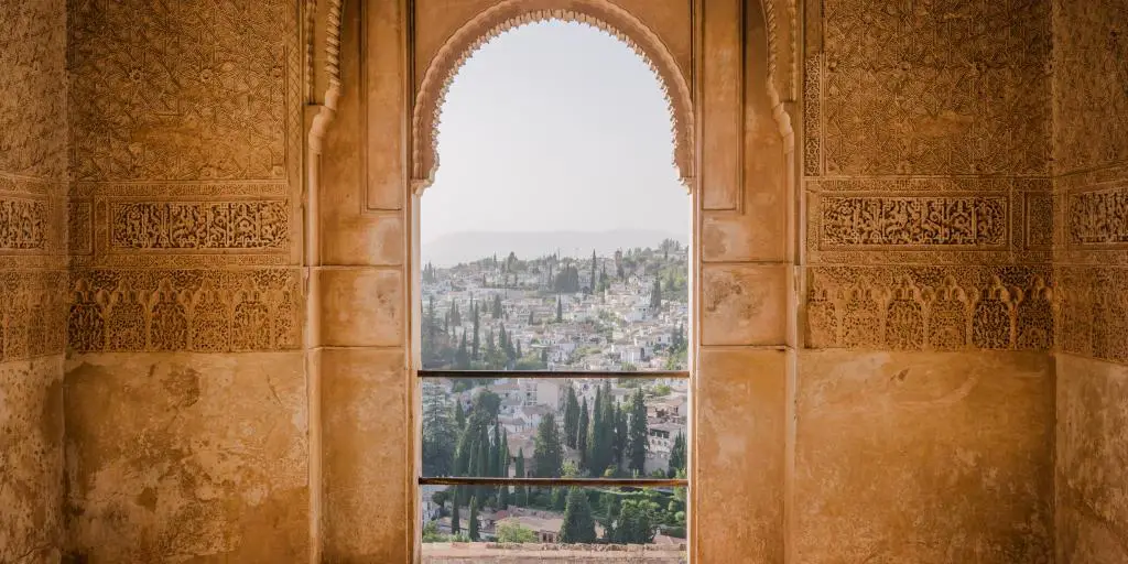 Los tejados y árboles de Granada vistos a través de una puerta morisca en la fortaleza de la Alhambra