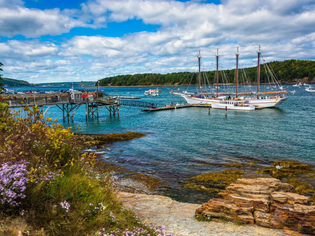 Costa rocosa y vista de barcos en el puerto de Bar Harbor, Maine.