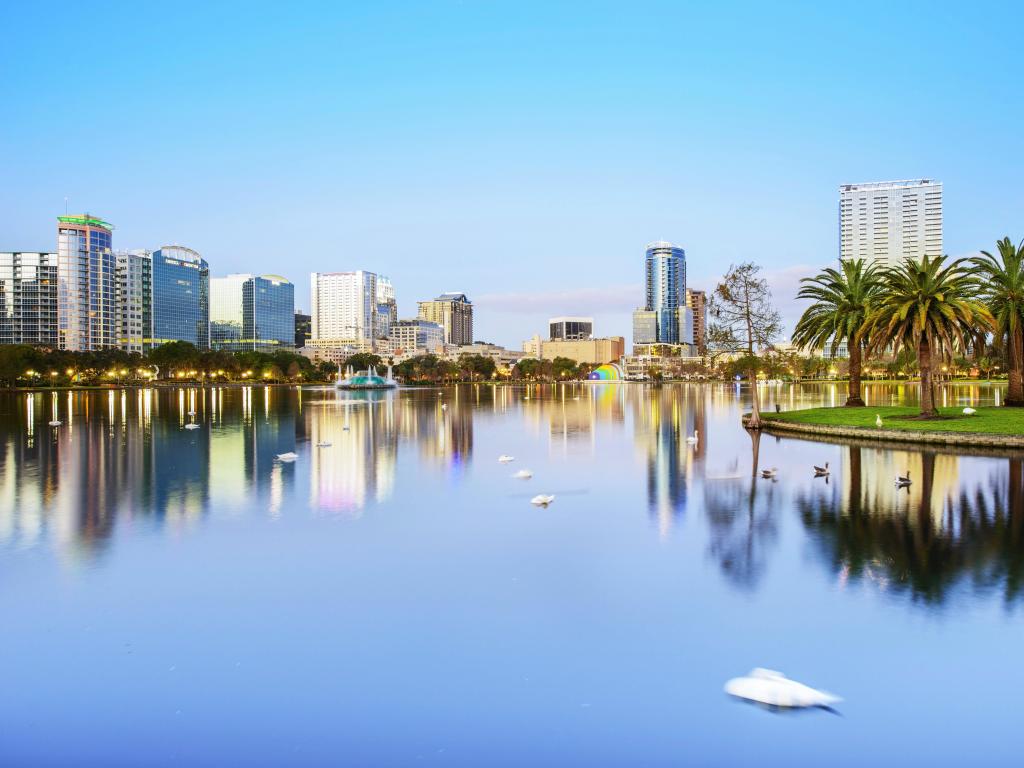 Orlando, Florida, EE.UU. con el panorama del horizonte del centro sobre el lago Eola con rascacielos urbanos, palmeras tropicales y cielo despejado.