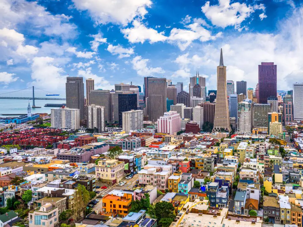 El horizonte de la ciudad de San Francisco, California, EE.UU. con un puente en la distancia, edificios coloridos en primer plano contra un cielo azul.
