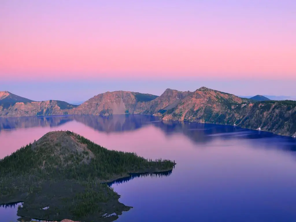 Cielo rosa sobre un lago azul tranquilo con parte del borde del cráter empinado a la vista