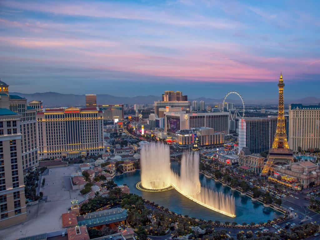 Las Vegas, Nevada, EE.UU. con una vista iluminada Las fuentes del Hotel Bellagio y el Strip de Las Vegas al atardecer.