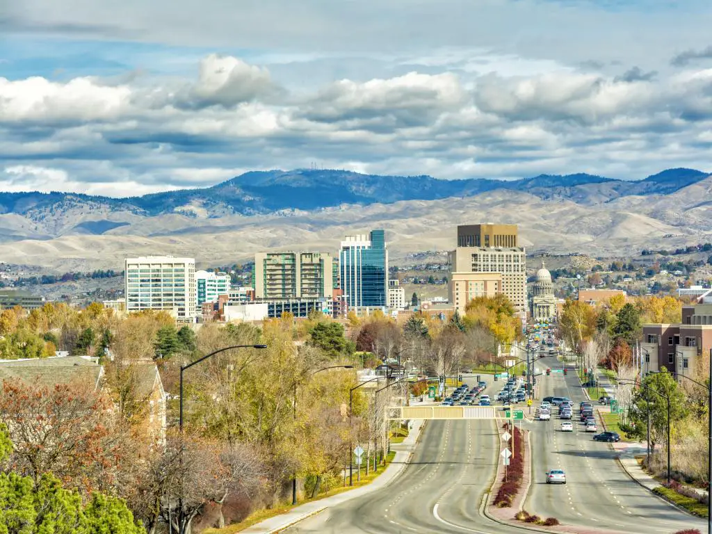 Boise, Idaho, EE. UU. Con una calle que conduce al edificio de la capital en otoño, montañas a lo lejos y un cielo nublado.