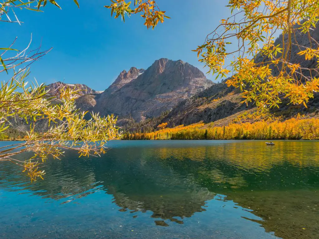 June Lake, California, EE.UU. con sauces dorados y árboles de Aspen en primer plano que rodean el lago y las montañas californianas de Sierra Nevada en el fondo en un día soleado.