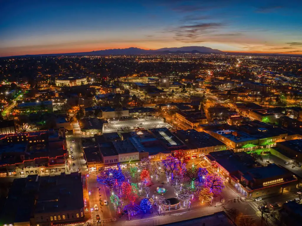 Paisaje urbano aéreo que muestra las luces de edificios bajos con árboles de Navidad de colores brillantes en la Plaza en primer plano