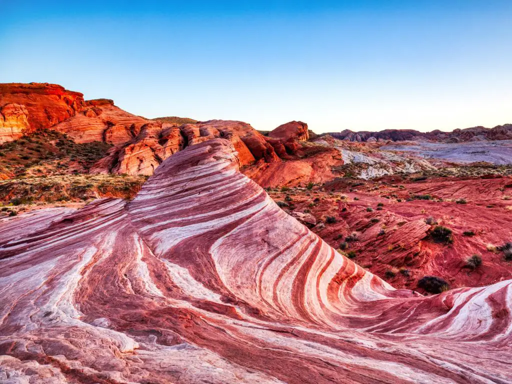 Parque Estatal Valley of Fire, Nevada, EE. UU. Con la ola de fuego tomada al atardecer y rodeada de rocas rojas en la distancia.